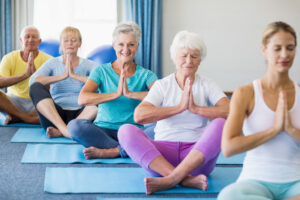 Eine Gruppe älterer Menschen macht Yoga in einem Fitnessstudio.