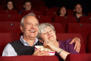 Ein älteres Paar sitzt in einem Kinosaal und schaut sich einen Film an.