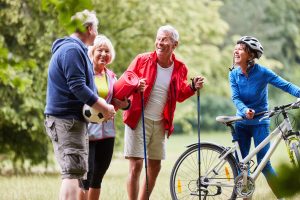 Ältere Menschen stehen beim Ausüben verschiedener Sportarten in der Natur zusammen.