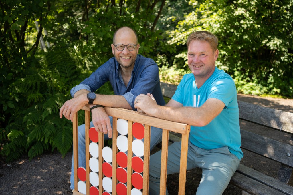 Spieleplus Gründer auf Parkbank mit Holzspiel Vier gewinnt