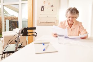 Seniorin blättert in Vertragsunterlagen des Pflegedienstleisters.