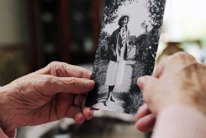 Senioren hält Foto vom Urlaub als junge Frau in den Händen