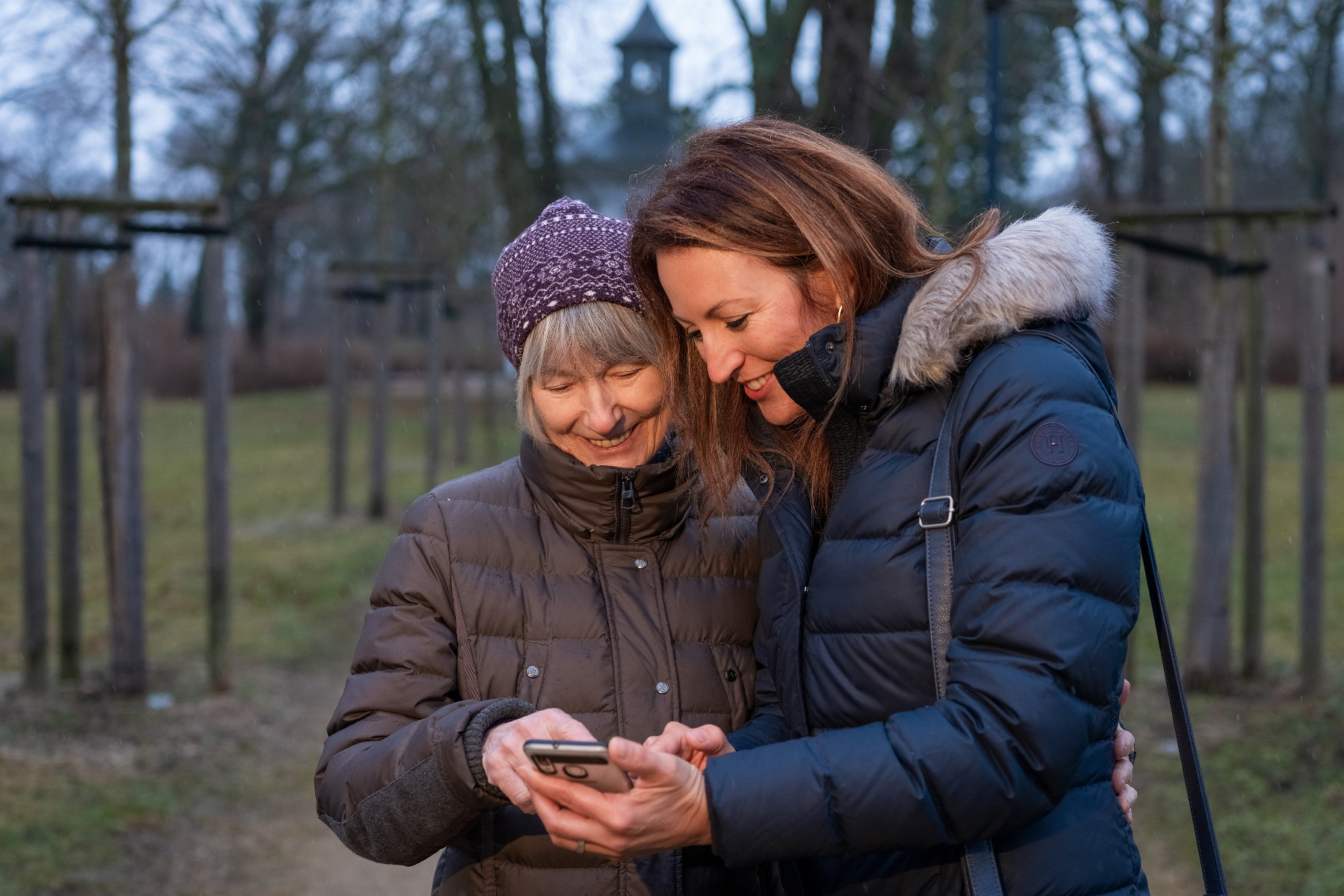Junge Altenpflegerin beschäftigt sich fröhlich mit Seniorin, um das Smartphone zu erklären.