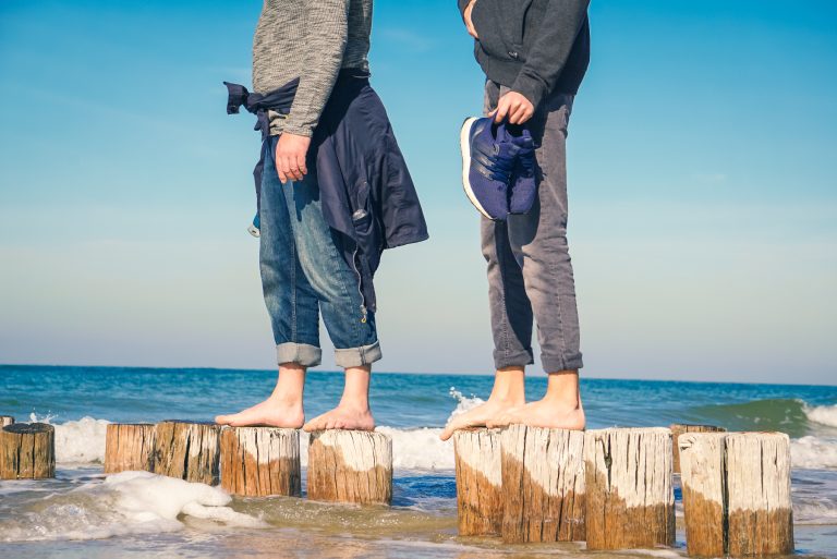Zwei junge Menschen halten das Gleichgewicht auf Stelen im Wasser.