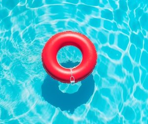 Ein roter Rettungsring liegt in einem kristallklaren Pool.