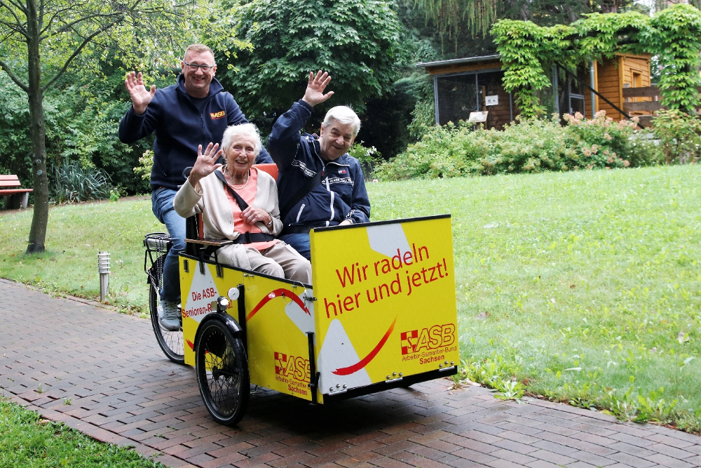 Senioren werden mit Fahrradrikscha gefahren und freuen sich.