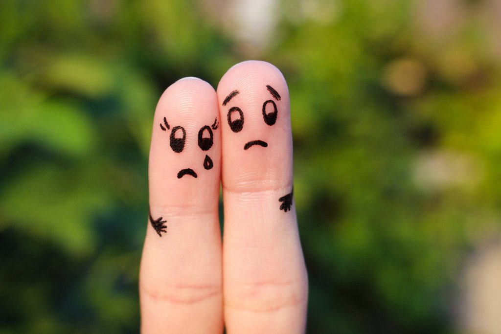 Zwei Finger mit aufgemalten traurigen Gesichtern stellen symbolisch dar, wie sie einander unterstützen.