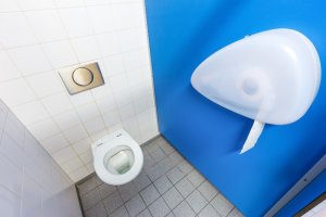 Toilettenpapier hängt sichtlich unerreichbar zur Toilette an der Wand.
