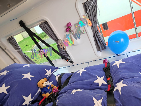 Der Innenraum vom ASB Wünschewagen zeigt ein Bett mit Sternen auf der blauen Bettdecke und ein Stofftier.