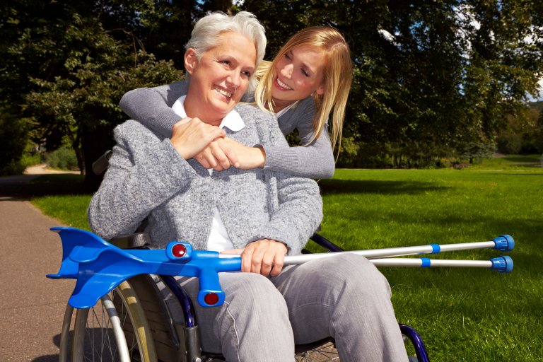 Frau sitzt nach einem Unfall mit Gehhilfen und Rollstuhl