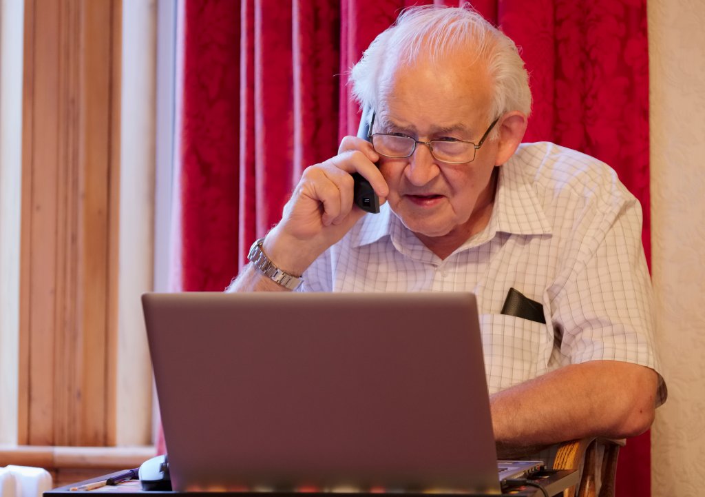 Rentner telefoniert und arbeitet am Computer